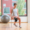 A woman, with one leg bent, sitting on a chair